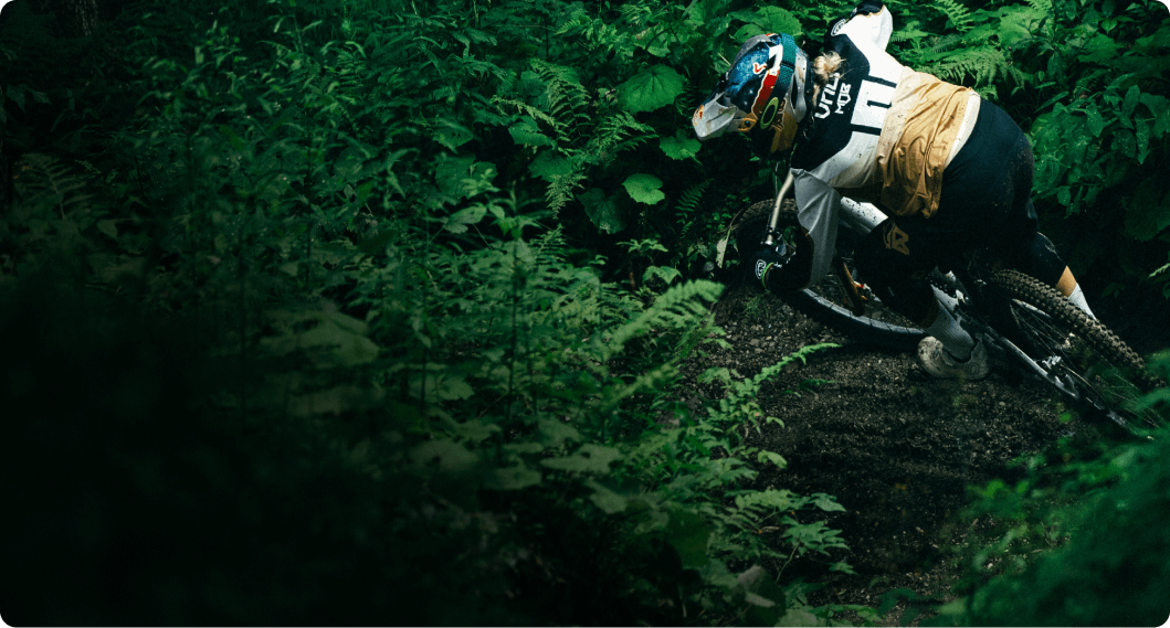 Vali Höll biking through a lush green forest.